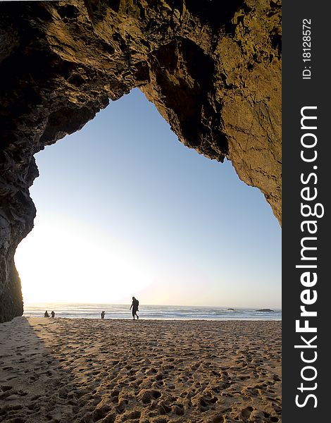 Tourist walking towards the, seen from a cave in the cliff. Tourist walking towards the, seen from a cave in the cliff