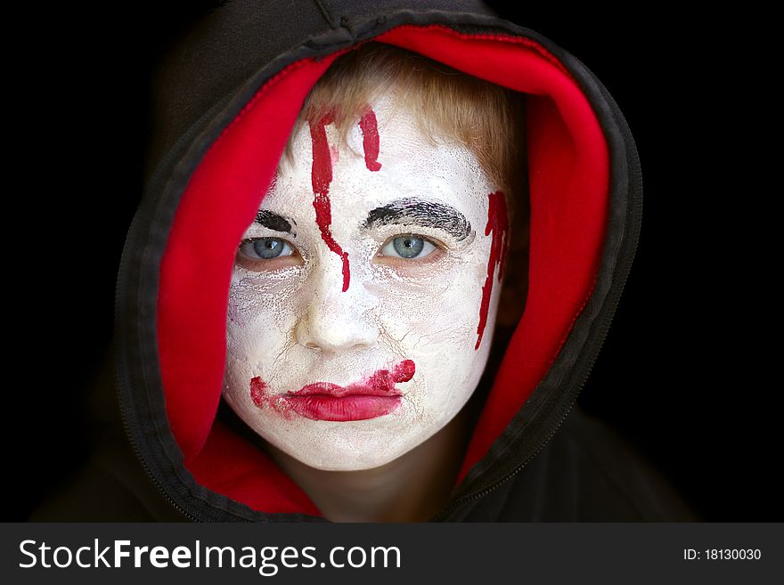 Boy in red hood with painted face on halloween.