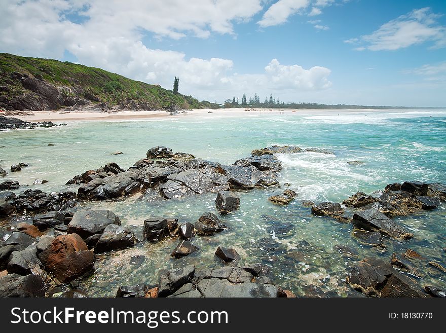 Australian beach during the day with rocks in foreground