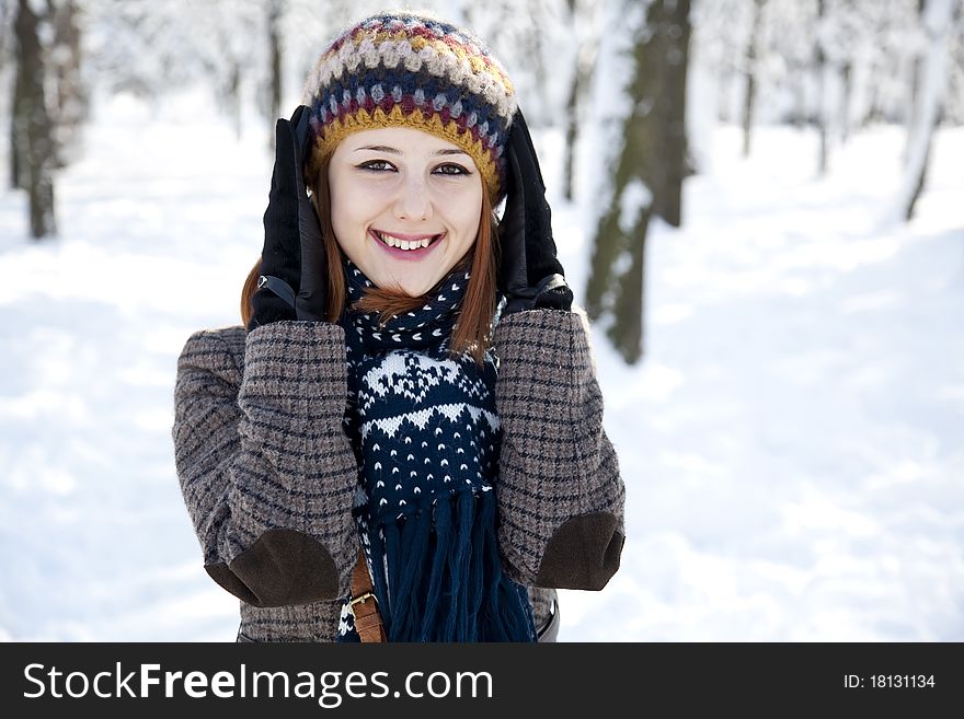 Beautiful young red-haired woman in winter park. Outdoor shot.