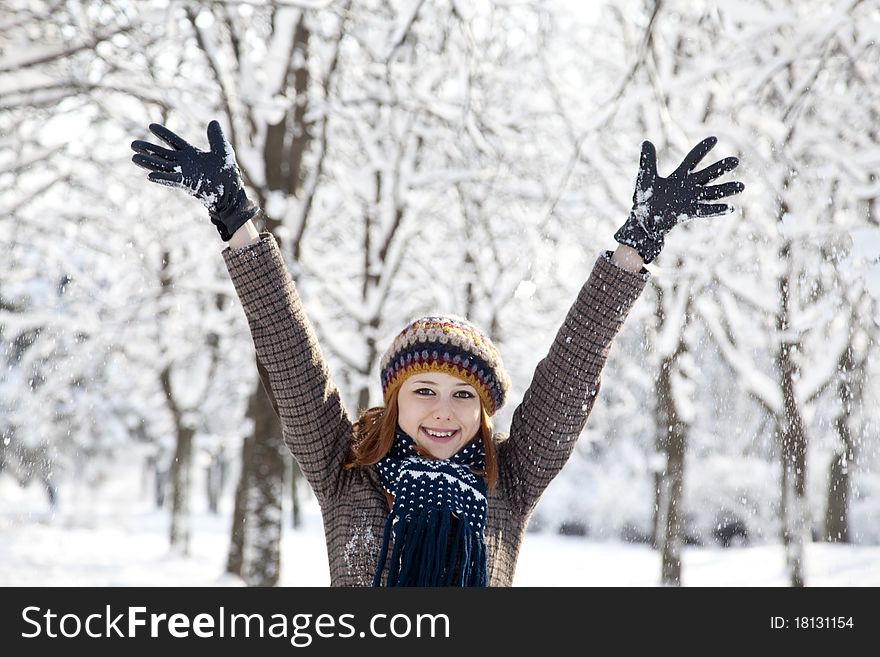 Beautiful young red-haired woman in winter park. Outdoor shot.