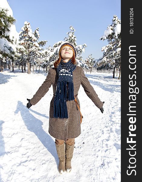 Beautiful young red-haired woman in winter park. Outdoor shot.