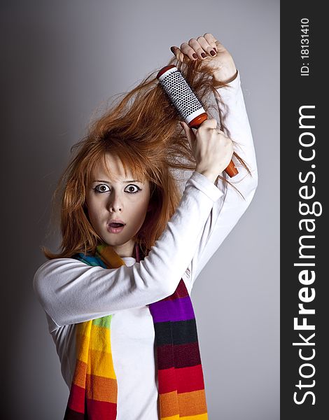 Sad red-haired girl with comb. Studio shot.