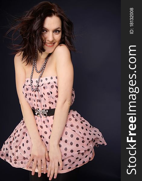 Happy brunette woman with pink dress, studio shot