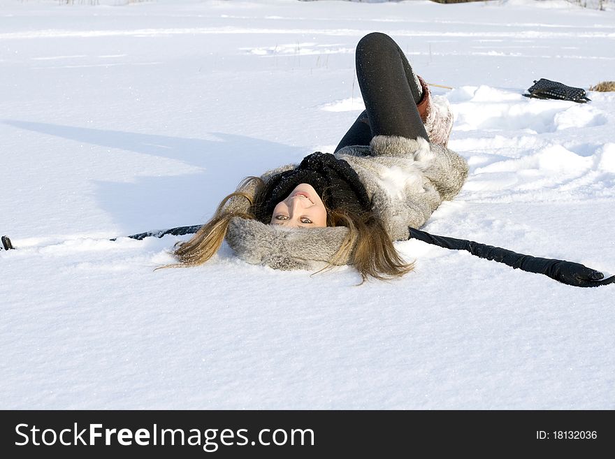 Happy girl lying in snow on a field