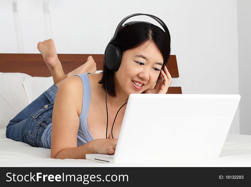 An Asian woman listening to music on a laptop. An Asian woman listening to music on a laptop