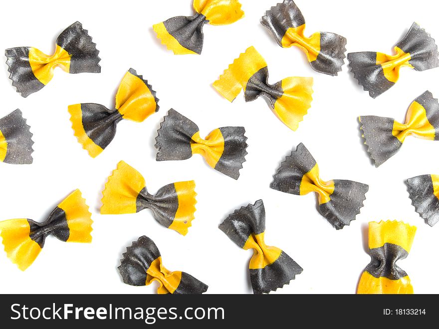 The yellow and black pasta is isolated on a white background. The yellow and black pasta is isolated on a white background