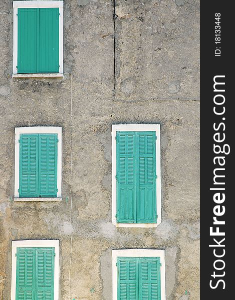 Closed green window shutters on a gray house facade