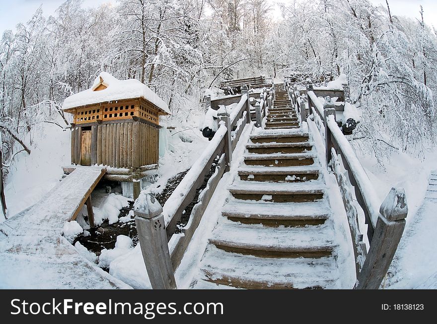 Snow-covered wooden ladder and booth for bathing against winter wood. Snow-covered wooden ladder and booth for bathing against winter wood