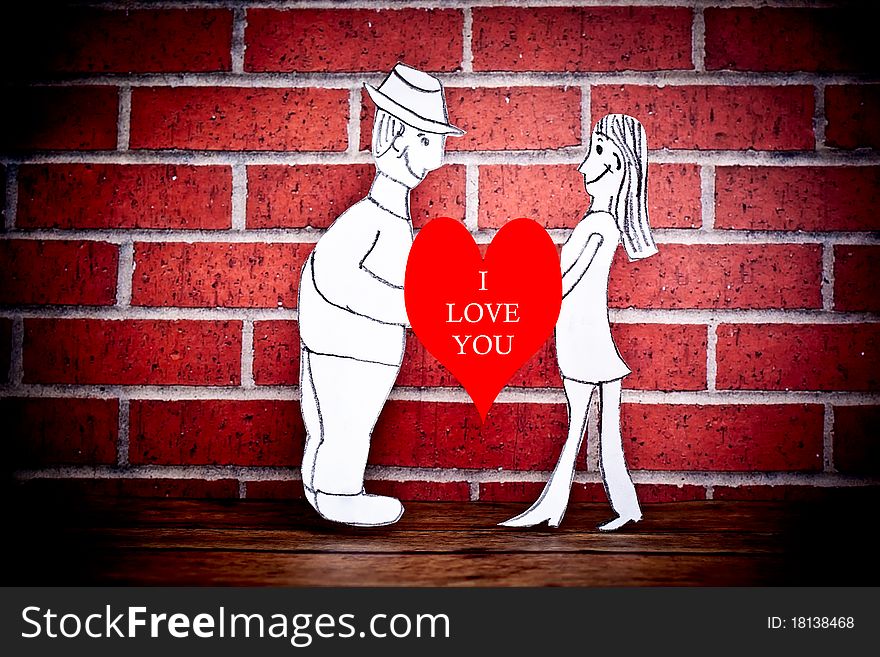 A couple drawn on paper and photographed on a wood floor in front of a brick wall. A couple drawn on paper and photographed on a wood floor in front of a brick wall.