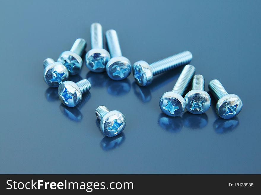 Many metal bolts on a grey background