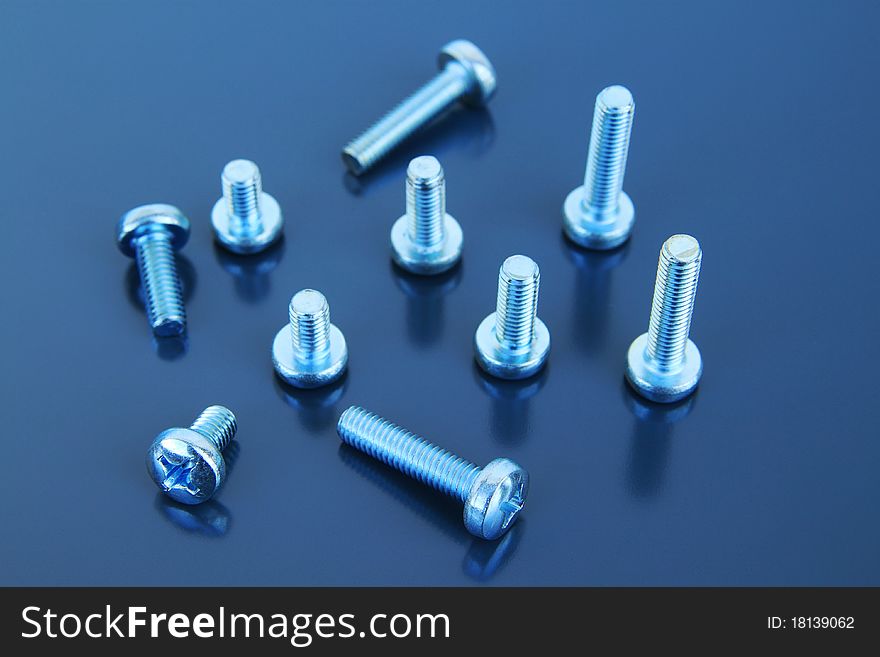 Many metal bolts on a grey background