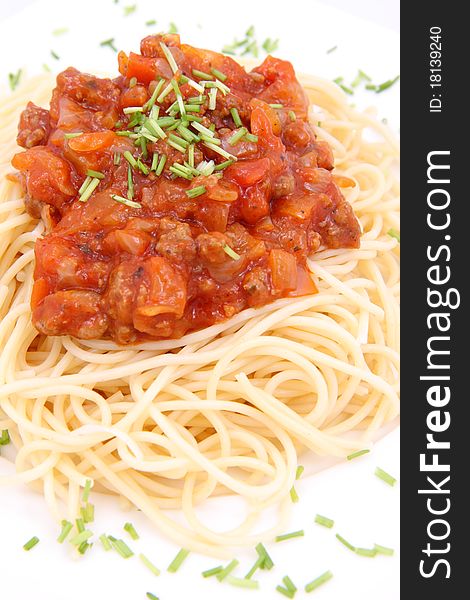 Spaghetti bolognese on a plate decorated with some chives