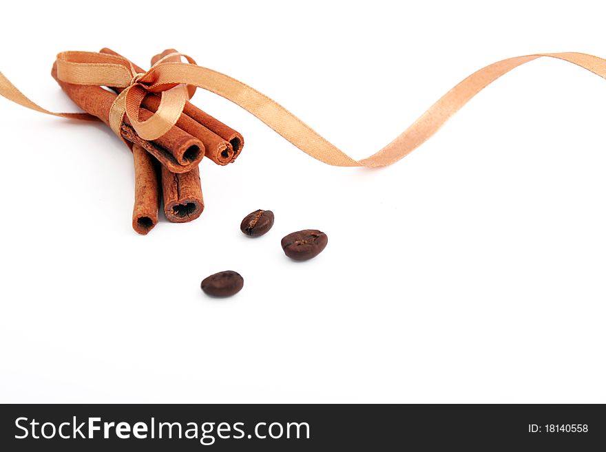 Cinnamon sticks bonded golden ribbon and coffee beans on a white background