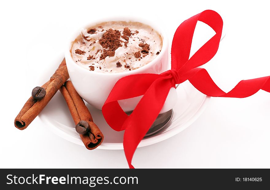 Cup of coffee with cream, cinnamon and red bow