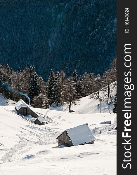 Mountain huts in winter with forest and mountains in the background. Mountain huts in winter with forest and mountains in the background
