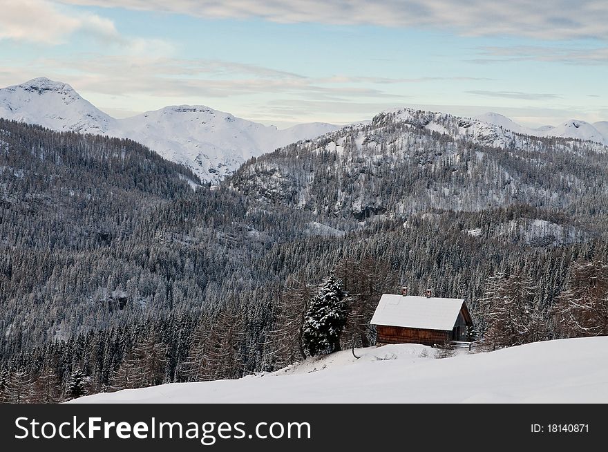 Mountain hut in winter with forest and mountains in the background. Mountain hut in winter with forest and mountains in the background