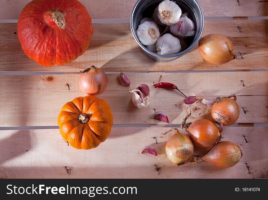 Onion, garlic and pumpkins on a wooden desk in sun shine