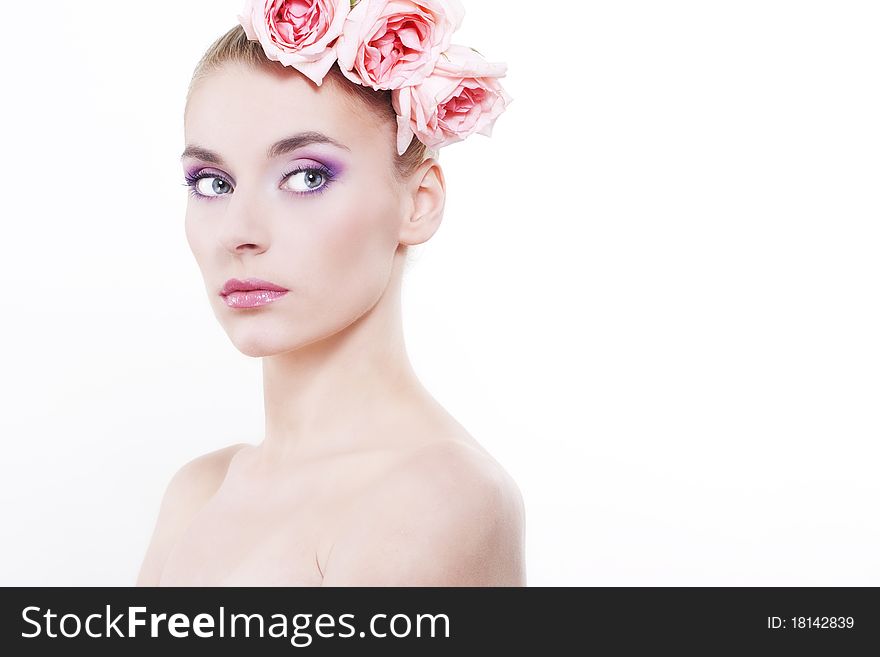 Portrait of young beautiful woman with roses in hair, on white background