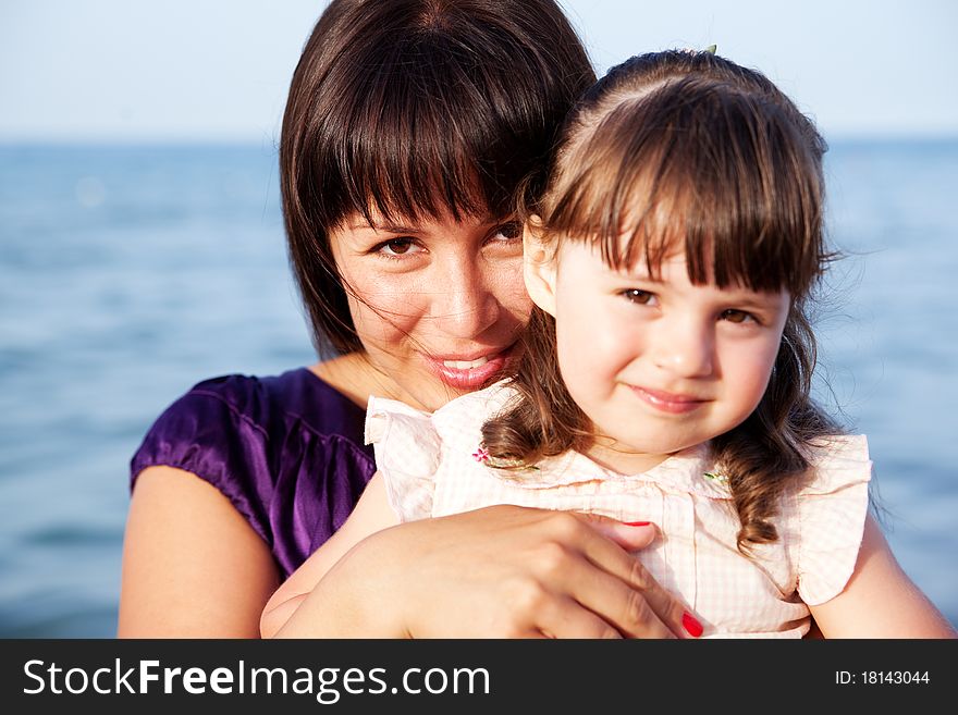 Mother hugging her daughter on sea background