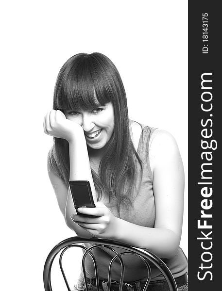 The young girl sitting on a chair with a mobile phone in a hand