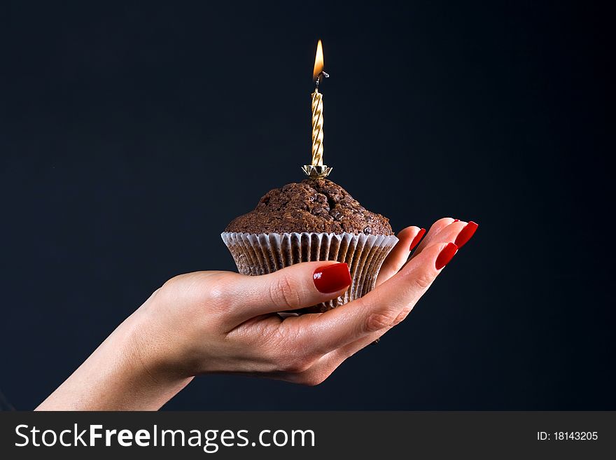 Muffin with a candle in the palm of a girl