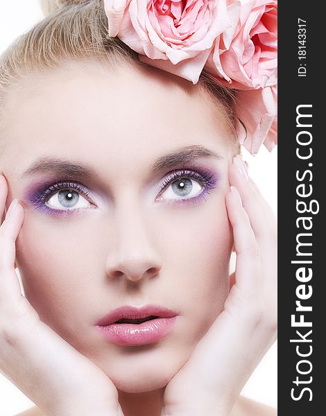 Portrait of young beautiful woman with roses in hair, on white background