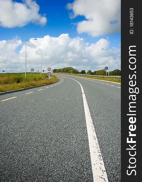 New motorway with road markings and blue sky with clouds
