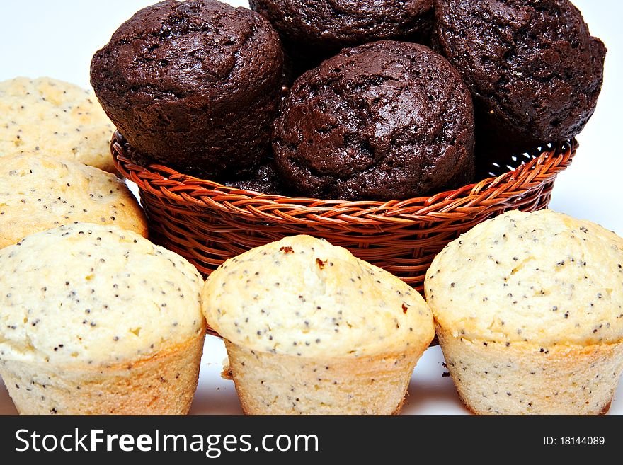 Basket filled with chocolate muffins and lemon poppy seed muffins in front on white background. Basket filled with chocolate muffins and lemon poppy seed muffins in front on white background