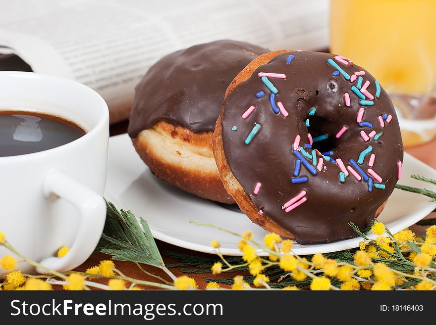 Chocolate donut served with coffee and orange juice. Chocolate donut served with coffee and orange juice.