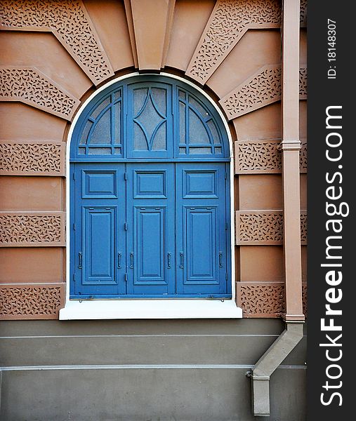 Blue window on brown wall of royal Thai palace in Bangkok, Thailand