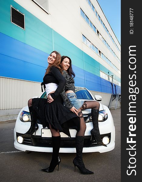 Two beautiful girls friend and stylish white sports car on the background industrial building. Two beautiful girls friend and stylish white sports car on the background industrial building
