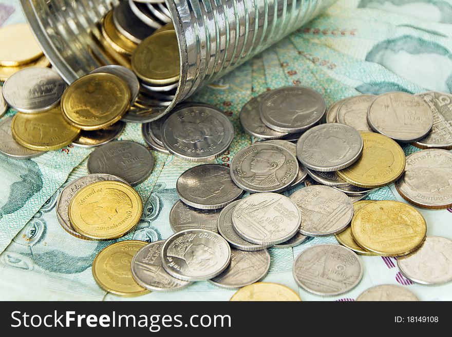 Thai banknotes and coins flowing out of the can