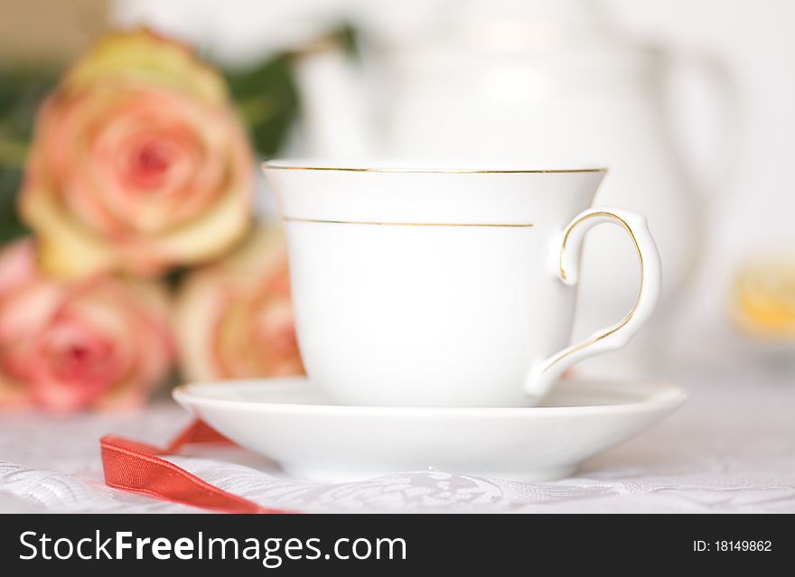 Teacup on table against roses. Teacup on table against roses