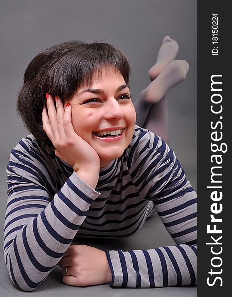 Casual woman smiling on the floor isolated over a white background