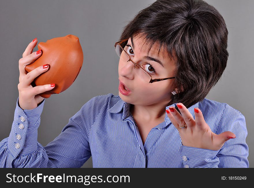 Young woman trying to get money from her piggy bank