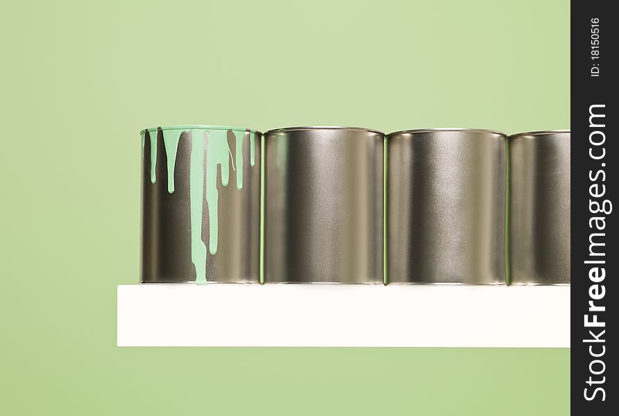 Paintcans in a row on green background