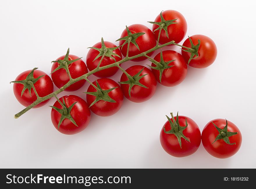 Ripe cherry tomatoes on a branch, isolated on white.