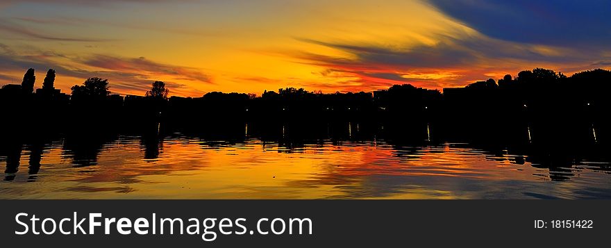 Brilliantly colorful sky at sunset reflecting in a perfectly calm lake. Brilliantly colorful sky at sunset reflecting in a perfectly calm lake