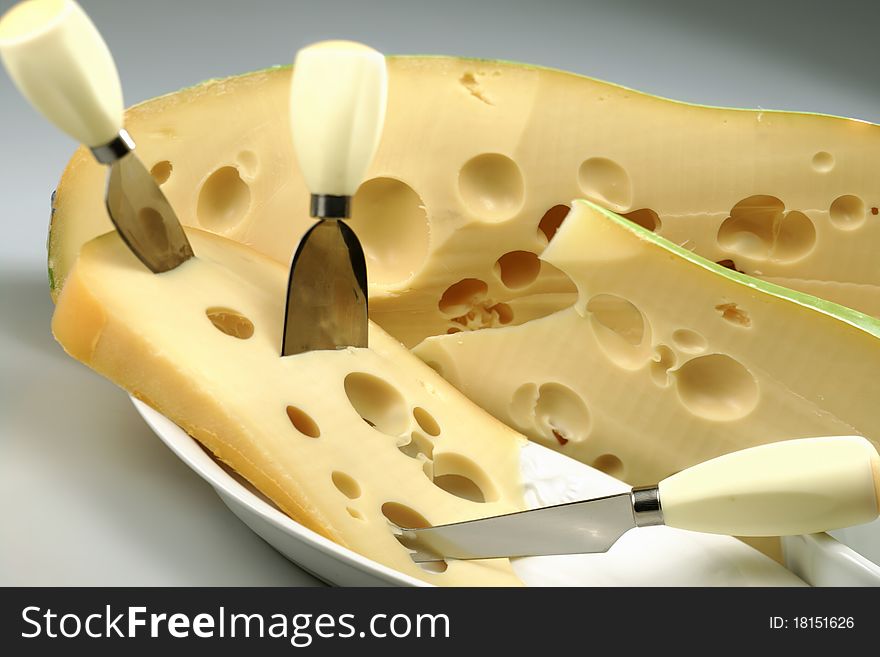 Dish with tipical Swiss cheese with holes and cheese knives
