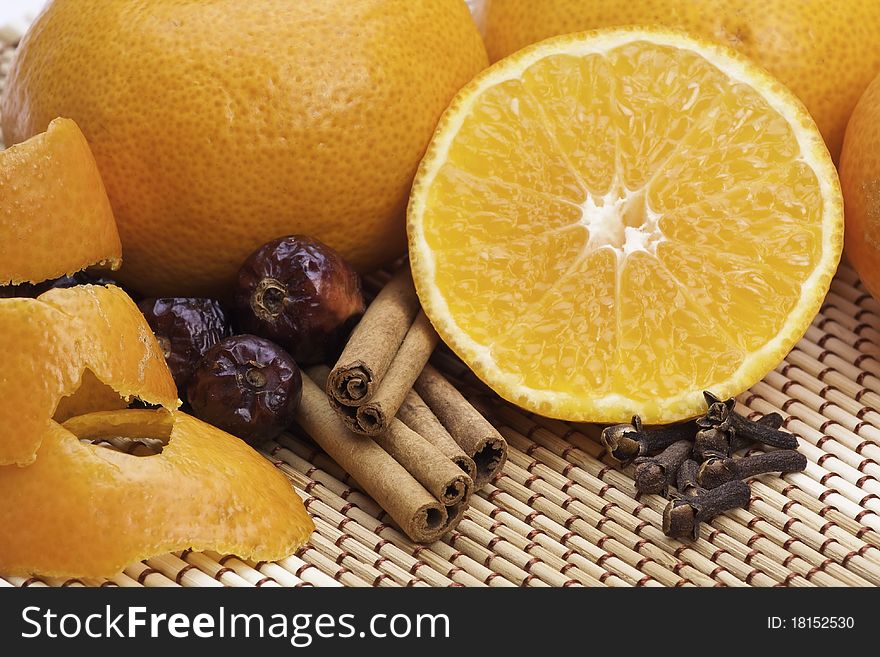 Oranges with cinnamon and spices on bamboo pad