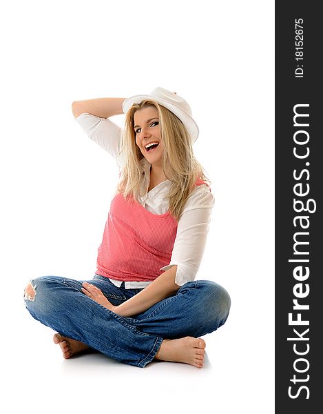 Young casual smiling woman in white hat sitting on the floor having fun isolated