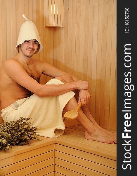 Young handsome man in a towel relaxing in a russian wooden sauna. Young handsome man in a towel relaxing in a russian wooden sauna