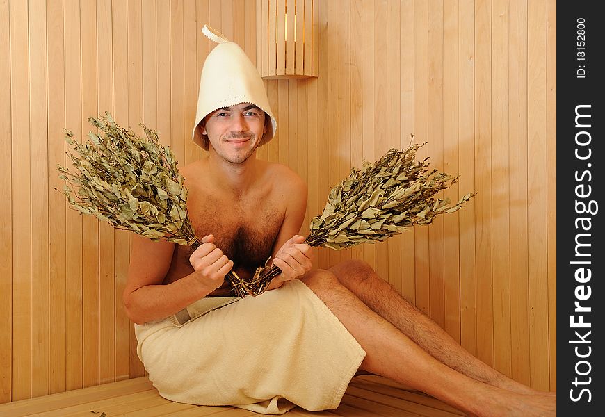 Young handsome man in a towel relaxing in a russian wooden sauna. Young handsome man in a towel relaxing in a russian wooden sauna
