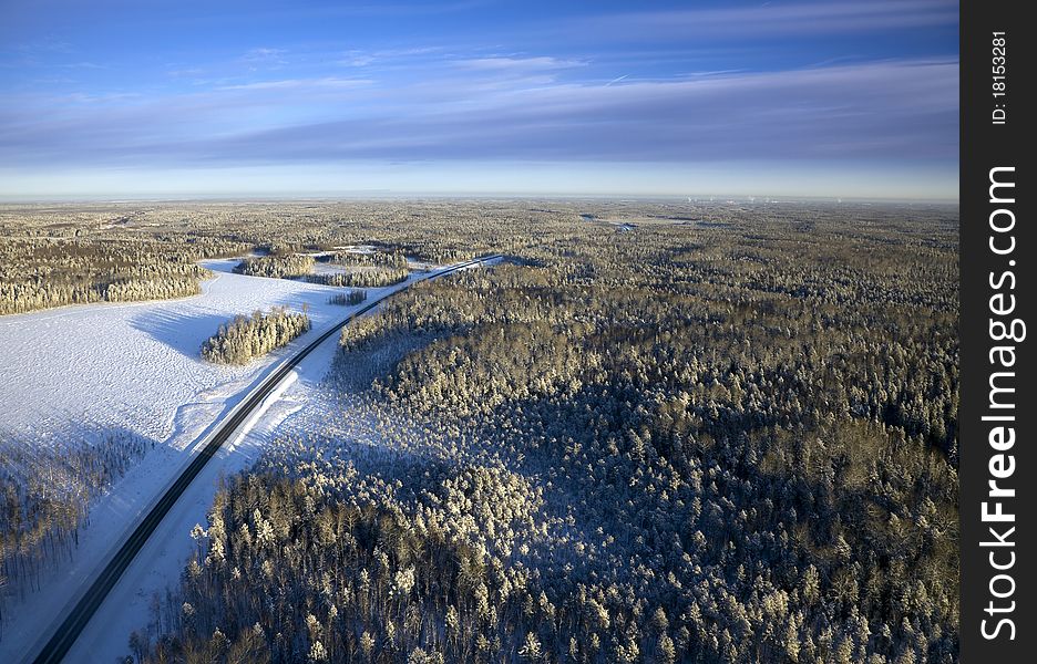 Top view of a highway that is located in a winter forest on a frosty day. Top view of a highway that is located in a winter forest on a frosty day.