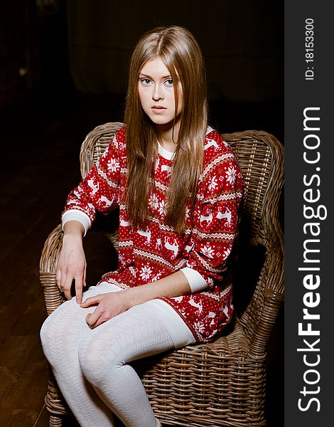 Cute woman sits in a chair wearing a sweater with the reindeer