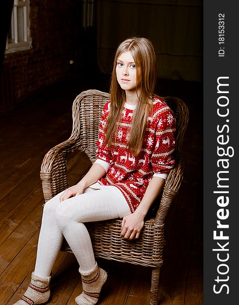 Cute woman sits in a chair wearing a sweater with the reindeer