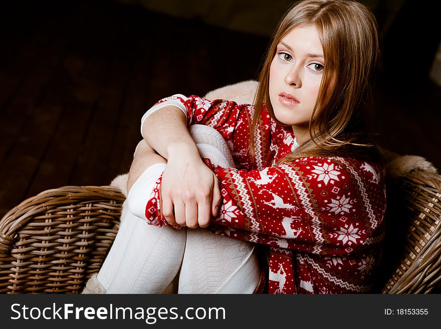 Cute woman sits in a chair wearing a sweater with the reindeer