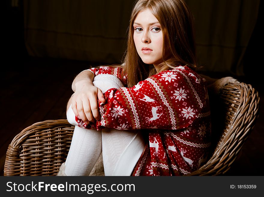 Cute woman sits in a chair wearing a sweater with the reindeer