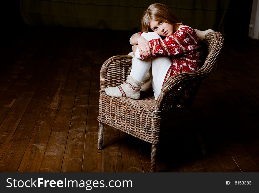 Cute woman sits in a chair wearing a sweater with the reindeer